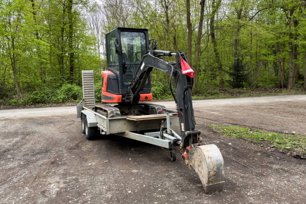 A Small Excavator Standing On A Car Trailer Rests Its Bucket On The Ground.